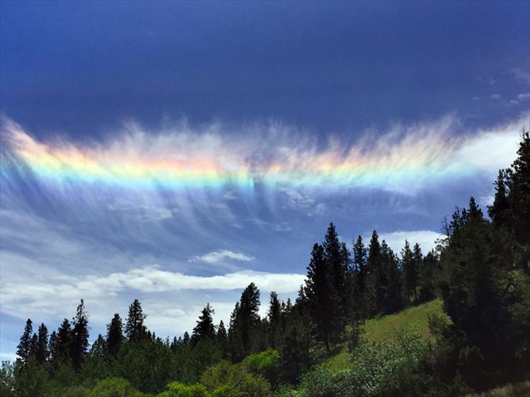 Wispy cirrus clouds filled with ice crystals produce prism effect colors in the sky known as sundogs.