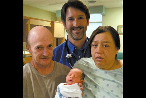 Phillip Shourds holds his newborn baby, Phillip Harvey Shourds, Jr., alongside mom Kendra Kenmille. Little Phillip was delivered shortly before noon on New Year’s Day by Dr. John Williams, center, at St. Luke Community Hospital.