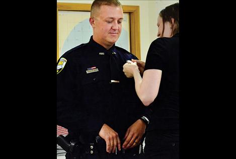 Ronan Police Officer Brandon Smith’s wife, Melissa Smith, pins his new badge on his uniform.
