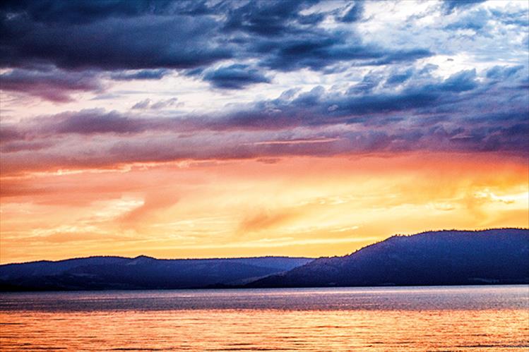 Storm clouds gather above Flathead Lake at sunset.