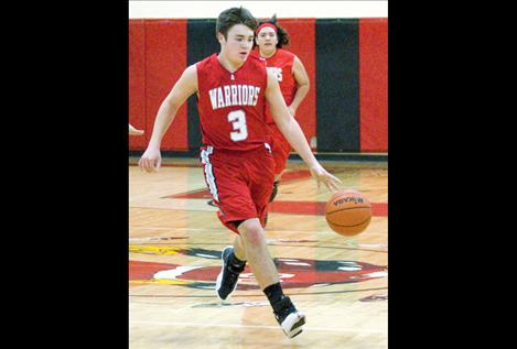 Junior Zane Ligas brings the ball out of the backcourt during the Warriors’ game against Two Eagle on Saturday. Arlee won, 107-68, and Ligas contributed 22 points for his team. 