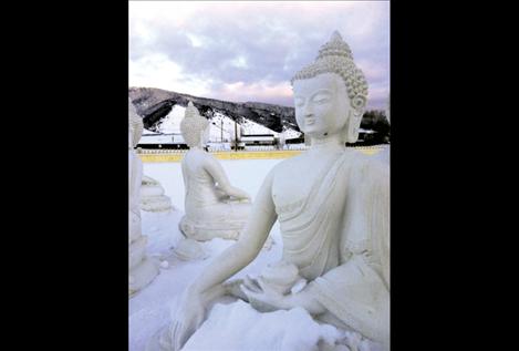 Snow covers ground, mountains and statues alike during a chilly sunset at the EWAM Garden of 1,000 Buddhas