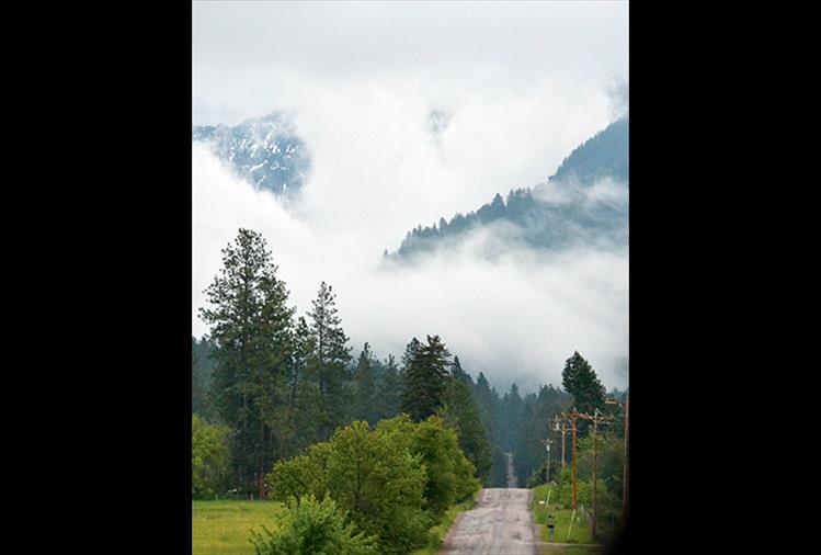 North Crow Road heads east into clouds that hang low over the Mission Mountains during September.