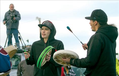 Ryan Upham and Antoine Paul drum and sing during a round dance after the Idle No More march as SKC professor Frank Tyro films the event from atop a vehicle.