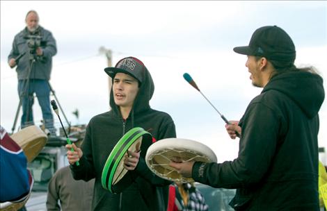 Ryan Upham and Antoine Paul drum and sing during a round dance after the Idle No More march as SKC professor Frank Tyro films the event from atop a vehicle.