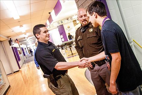 Brian Hines and Nate Lundeen greet student John Baker Street at Polson High School.