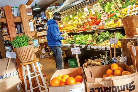 Pete Cox restocks locally-sourced vegetables at the Camas Organic Market in Hot Springs.