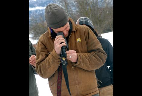 Larson uses the wrong end of binoculars as a field microscope to examine an owl pellet. 