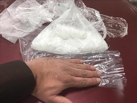 Law enforcement officers process a pound of methamphetamine confiscated morning from a vehicle that slid off Highway 28.