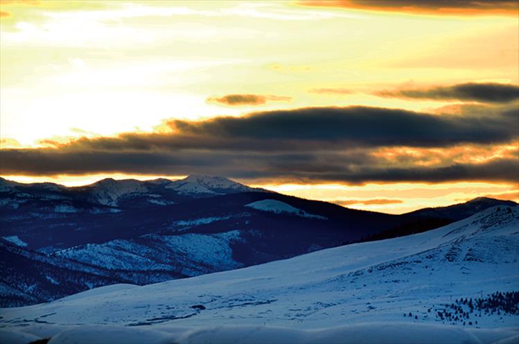 Wild clouds cascade of the Bison Range mountains at sunset.