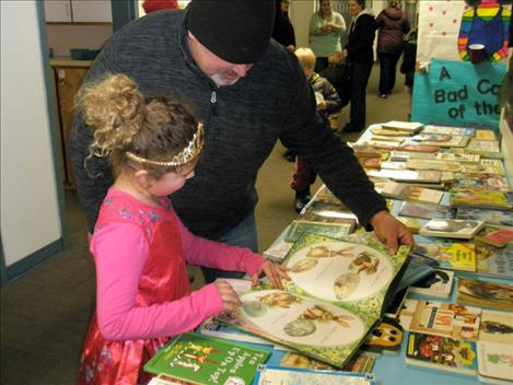 Second-grader Kyrsa Nash chooses a book with her dad, Wade Nash, at a book exchange. 