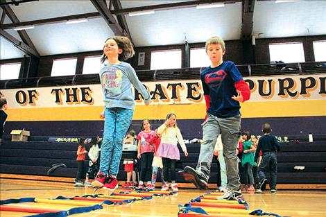 Second graders Sierra Symington, left, and Dominik Firestone hop and skip over ladder rungs at one of the Jump Rope for Heart stations March 1.