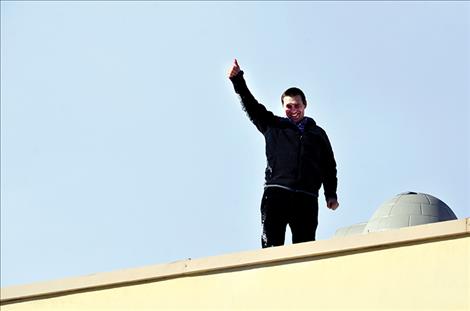 Principal Tyler Arlint shows kids, with a thumbs-up, that he made it on the roof.