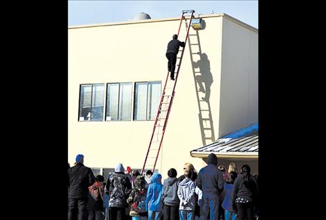 Principal Tyler Arlint climbs 33 feet to the roof.