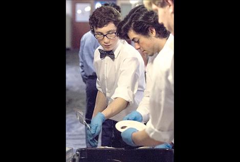 Members of the Mariners baseball team clean dishes during a black-tie dinner fundraiser.