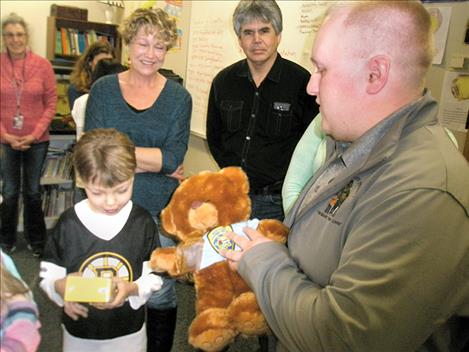 Joel DuMontier receives a teddy bear and camera from Montana Highway Patrol Trooper Zach Miller as DuMontier’s parents, Linda and Brian, watch during a Montana Hope Project event at Polson Middle School on March 15.