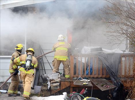 Firefighters prepare to douse flames in the entryway.