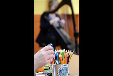 Harpist Debbie Conrad strums Celtic folk tunes while people color designs and explore Irish and Scottish culture March 22 at the library in Polson.