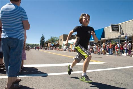 A young runner heads down Polson's Main Street during the 1776 Firecracker Fun Run.