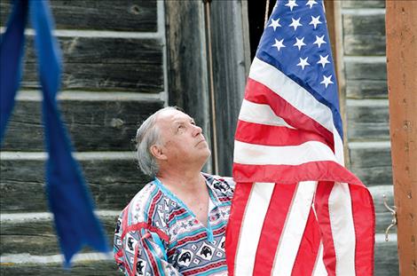 Fort Connah Restoration Society President Al Williams raises the flag during the opening ceremony.