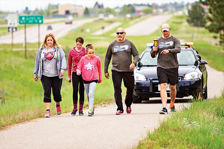 CSKT Police Chief Craige Couture, CSKT Fish and Game officer Brandon Couture and family carry the torch for Special Olympics Friday morning, along U.S. Highway 93 toward Pablo.