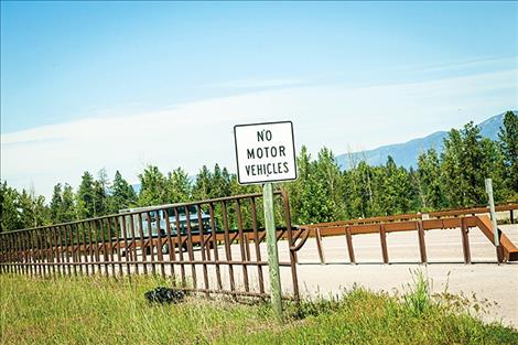 A guardrail located between the bicycle path and US 93 on the west side of the highway obscures drivers’ views of southbound traffic. The photo was taken from a driver’s side window of a sedan.