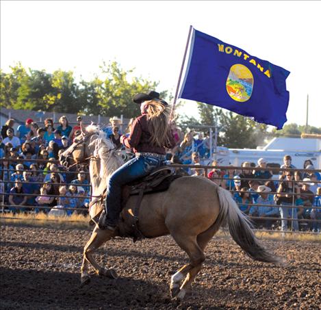 Michaela Blevins circles the arena bearing the Montana flag.