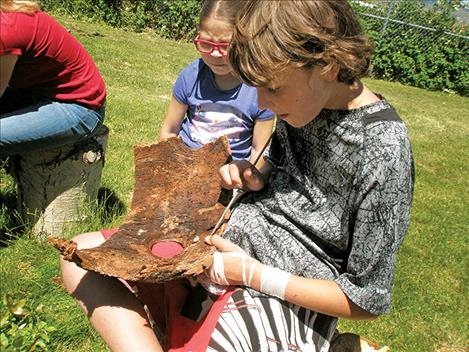 Cortlin Brisbin digs in ponderosa pine bark for insects while Savannah Plant looks on.