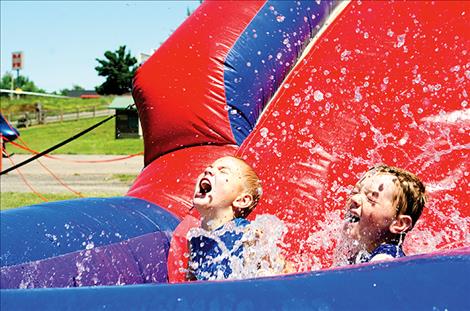 Castieo  Castiel, 6, and  Ronson Hout, 7,  splash down  in a pool of  water on a  slide set up  at the St. Ignatius  Firman’s Auction  for kids. The fire  department provided the water from one  of their trucks.
