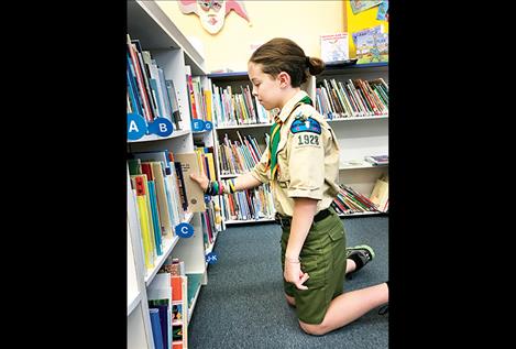 grader  Jeremiah  Jepson  peruses  books  on the  new  bookcase  he built  for the  West  Shore  Community  Library  as part  of his  Eagle  Scout  project.