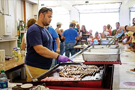 Volunteer fireman TJ Sheridan prepares sausages for visitors at the Arlee Fireman’s Breakfast.