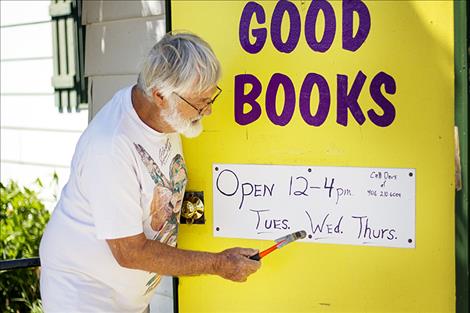 Dave Marshall hammers a sign on the door with the store’s hours.