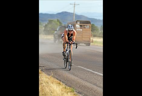 A triathlon cyclist shares the road with a truck.