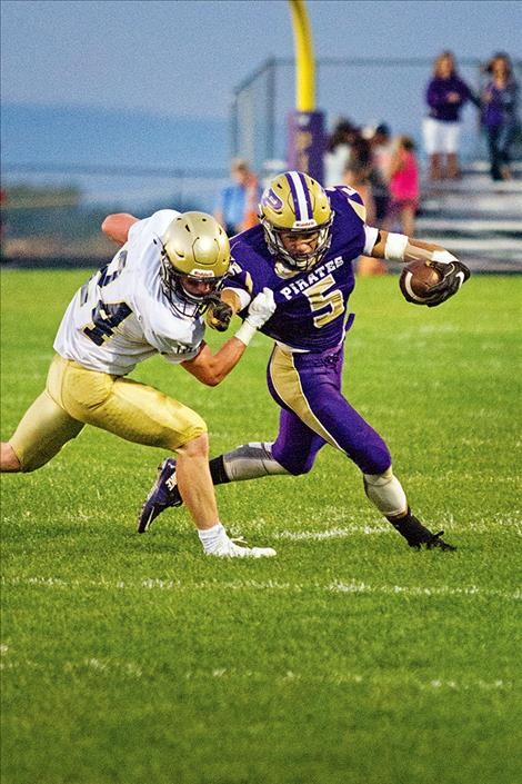 Pirate running back Koby  Garcia stiff  arms a  defender.