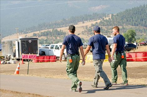 Firefighters walk through camp on a smoky morning.