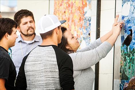 Terri Cleveland, along with her sons David and Nick, place a replica of her husband’s police badge in the mosiac mural at Riverside Park.