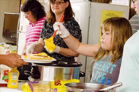 Volunteers serve dinner during a meal in St. Ignatius