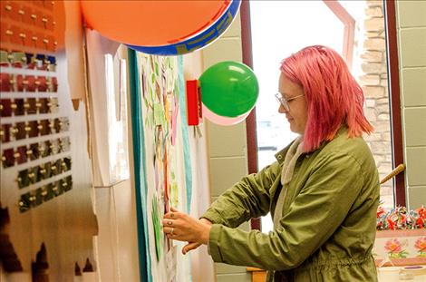 People attending the Baha’i celebration decorate a community unity tree with handprints, names and words of kindness. 