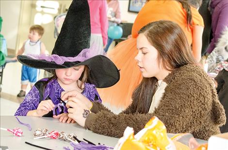 High school student Azia-Rain Umphrey helps a student with a craft.