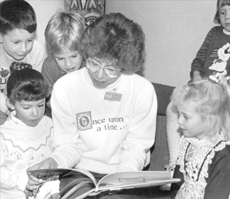 Marilyn Trosper reads to children during a story time hour at the library in Polson in the early 1990s. From left to right (front) are: Emily Fors, Marilyn Trosper and Andrea Mazurek. Behind them from left are: Ian Freemole, Kevin Owen and Jessica Bowers.