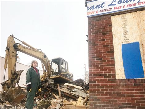 Owner Lori Peterson stands at the demolition pile of what used to be Dick’s Pheasant Lounge on Main Street in Ronan before it burned down.