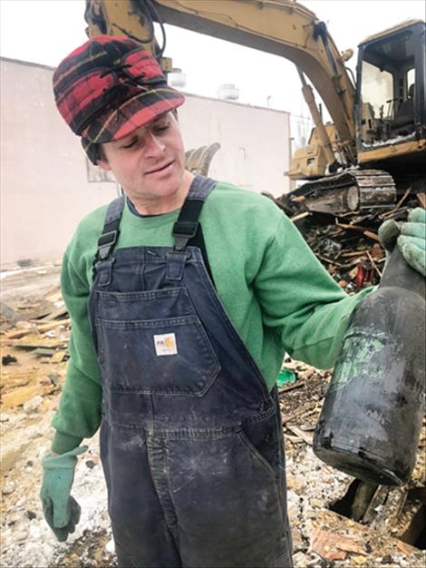 Mike Crockett shows off an old intact beer bottle that survived both the fire and his demolition.