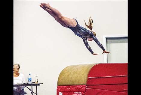 Chloe Cooper, of Golden Triangle Gymnastics in Conrad, competes as judge Robbie Goden watches.