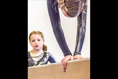 Lauren Collinge competes on the beam as teammate Ciri Nice watches.