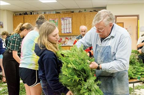 Florist Connie Plaissay helps St. Ignatius Middle School students create holiday boughs of cedar, pine and fir for the Dogs With Wings annual  fundraiser.  With the  proceeds,  students  purchase  Christmas gifts for children in need.
