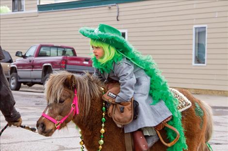 Sarah Templer reaches for candy to toss to the crowd as she parades down Main Street on her pony.
