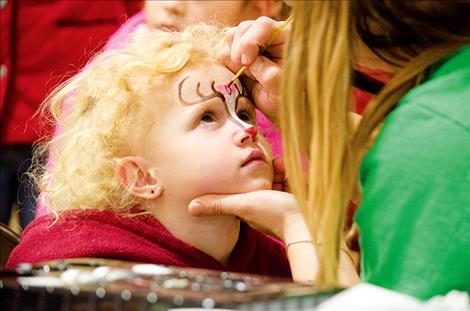 Alyeah Burckhard, 3, gets a reindeer painted on her face during the annual St. Ignatius Chamber of Commerce holiday carnival.