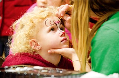 Alyeah Burckhard, 3, gets a reindeer painted on her face during the annual  St. Ignatius Chamber of Commerce holiday  carnival.