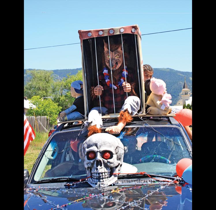 A caged creature howls and screams on top of a terrifying parade float.