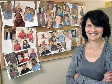 Nancy Hemphill stands next to a board with photos of foster grandparents.